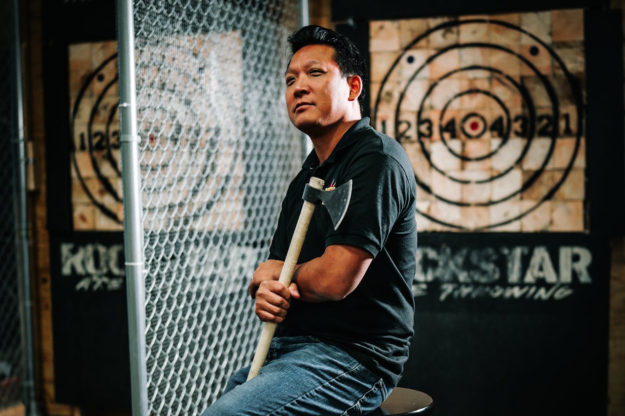 Mastering the First Impression: Your intriguing post title goes here Portrait of a man holding an axe at an indoor axe throwing range, surrounded by bullseyes.